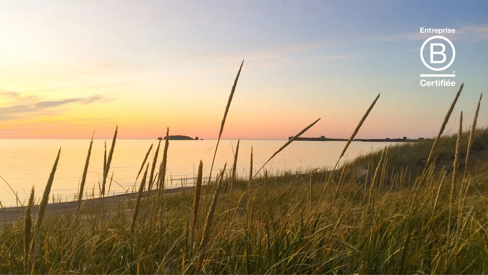 Coucher de soleil sur une plage des Îles-de-la-Madeleine avec le sceau d’entreprise certifiée B Corp d’Agence Nomade